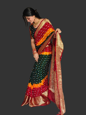 Woman in a colorful saree standing in a room with a couch and decorative items.